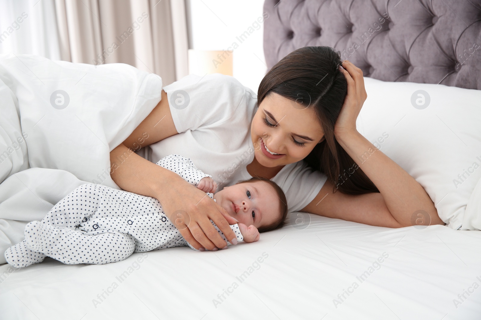 Photo of Happy woman with her cute baby on bed