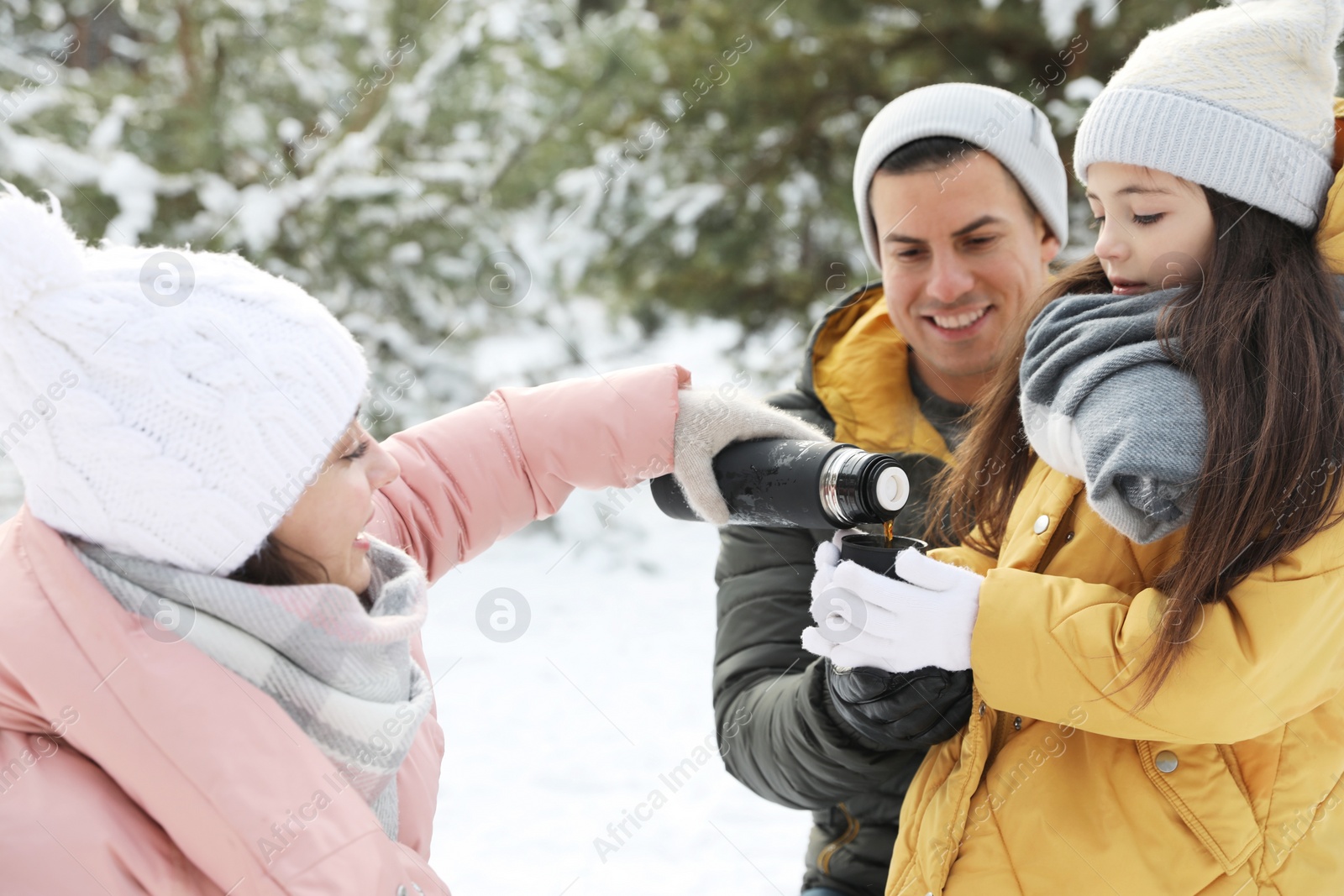 Photo of Happy family with thermos outdoors on winter day. Christmas vacation