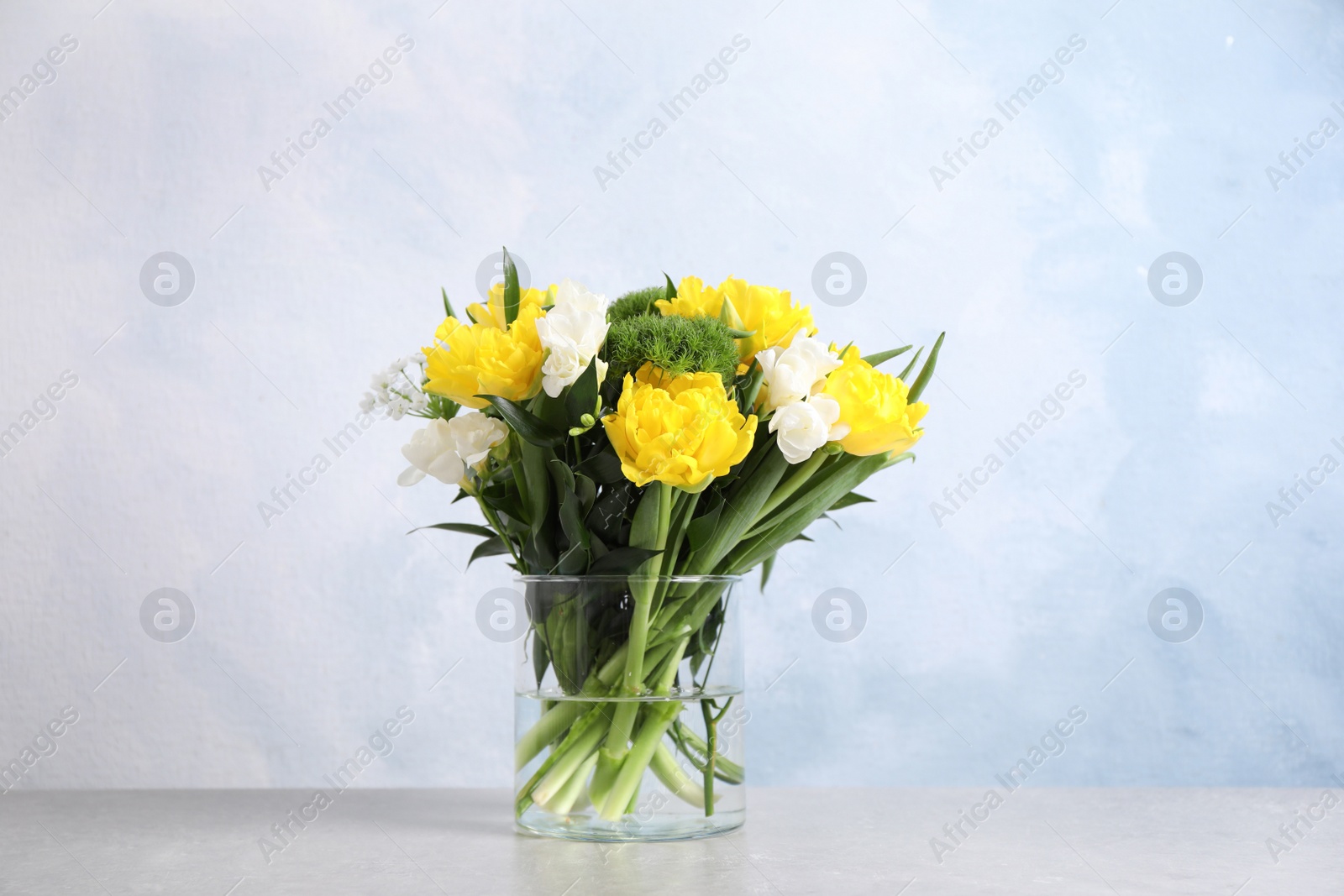 Photo of Beautiful bouquet with peony tulips on table against light blue background