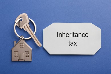 Photo of Inheritance Tax. Card and key with key chain in shape of house on blue background, top view