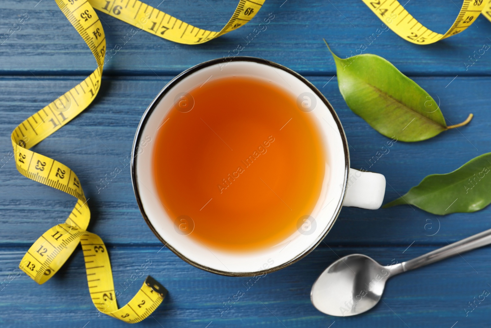 Photo of Flat lay composition with herbal diet tea and measuring tape on blue wooden table. Weight loss concept