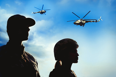 Silhouettes of soldiers in uniform and military helicopters patrolling outdoors