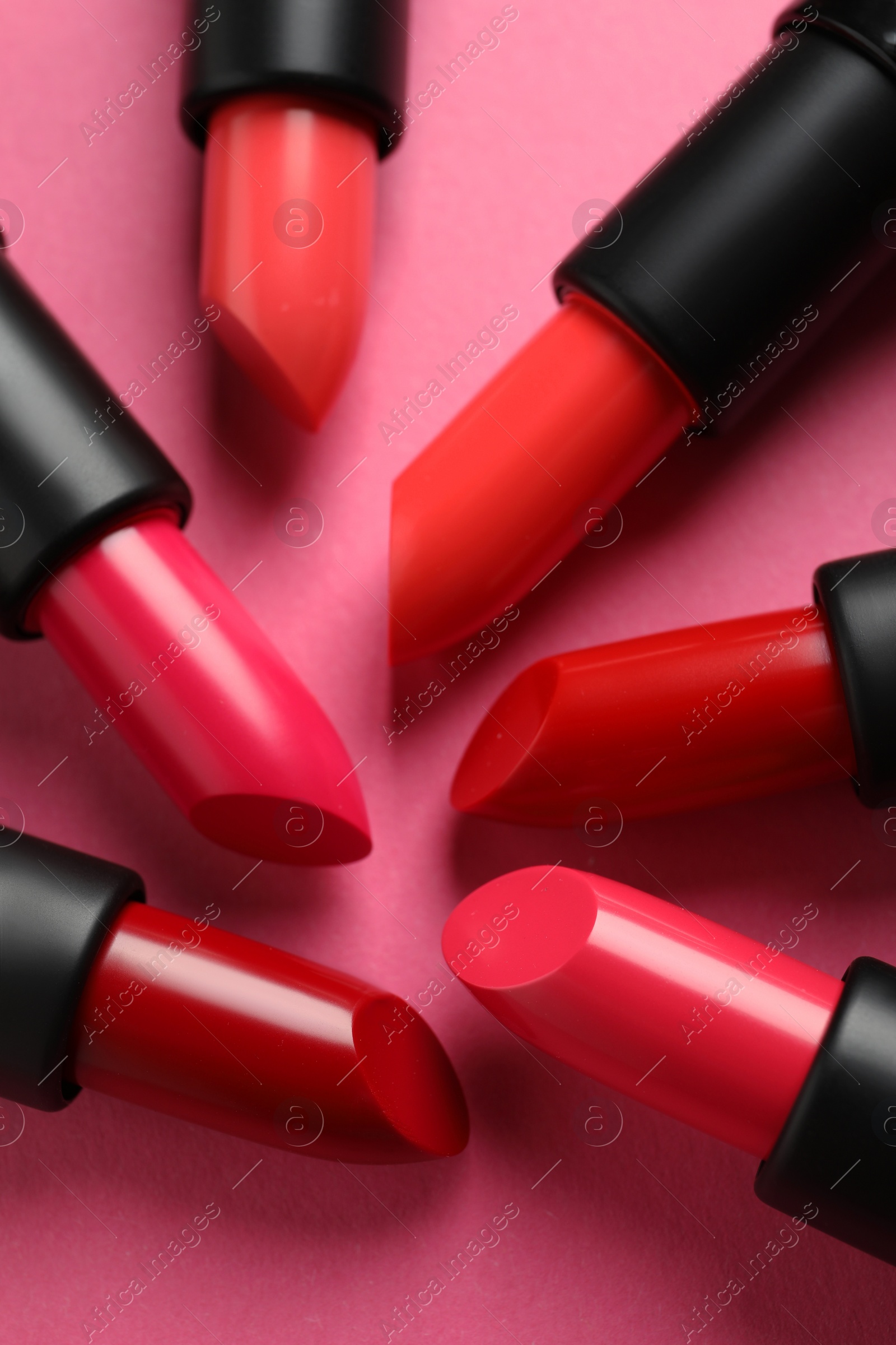 Photo of Beautiful lipsticks on pink background, flat lay