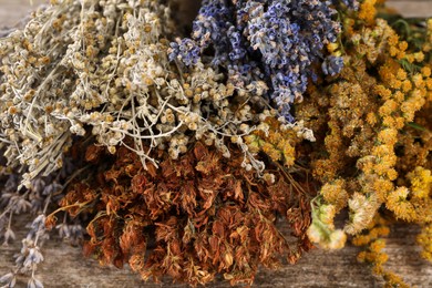 Photo of Many different dry herbs on wooden table, closeup