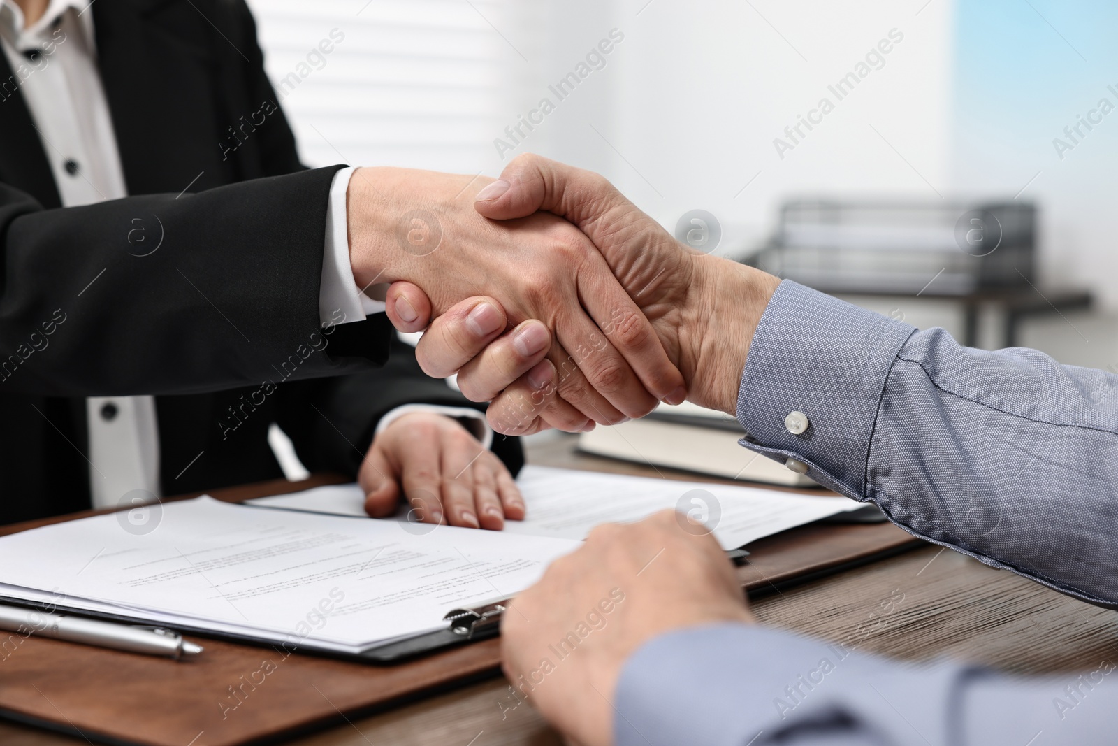 Photo of Lawyer shaking hands with client in office, closeup