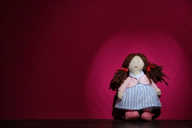 Photo of Abandoned doll on table against color background. Time to visit child psychologist