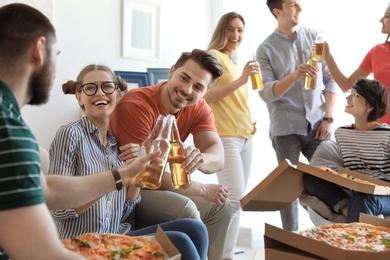 Young people having fun party with delicious pizza indoors