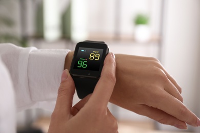 Image of Woman measuring oxygen level with smartwatch indoors, closeup