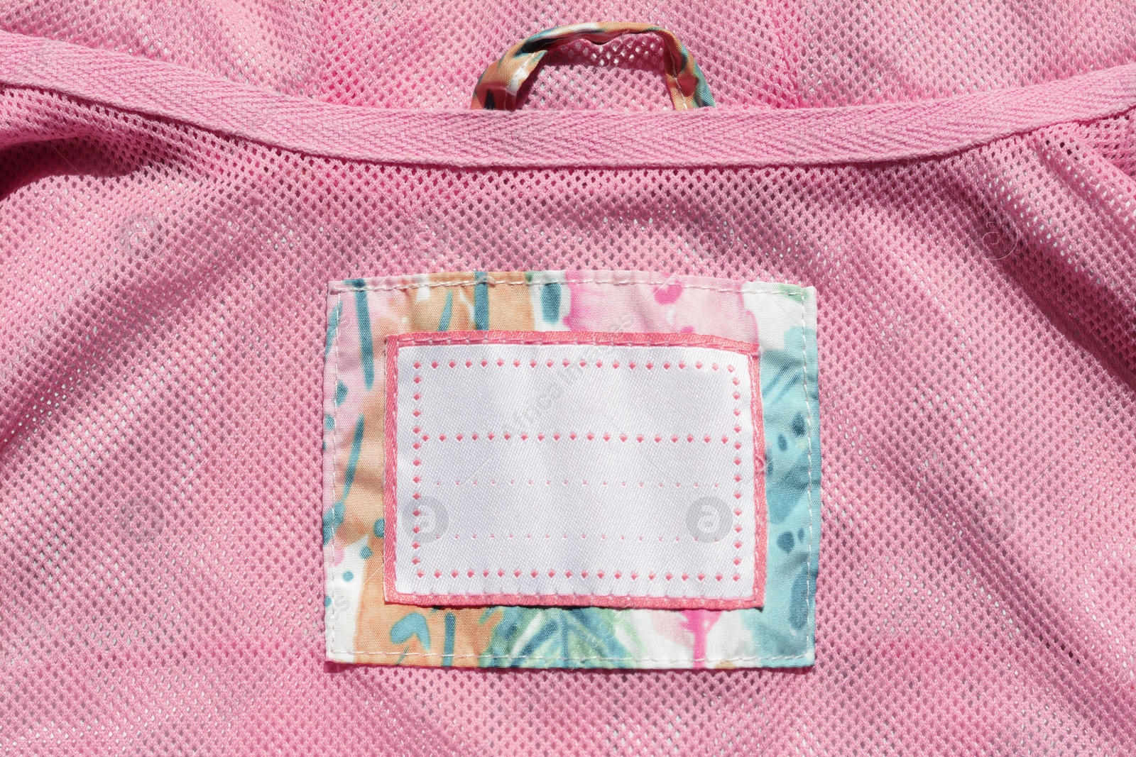 Photo of Clothing label on pink garment, top view