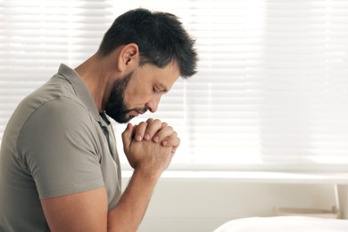 Photo of Religious man praying indoors. Space for text