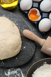 Photo of Fresh yeast dough and ingredients on black table, flat lay