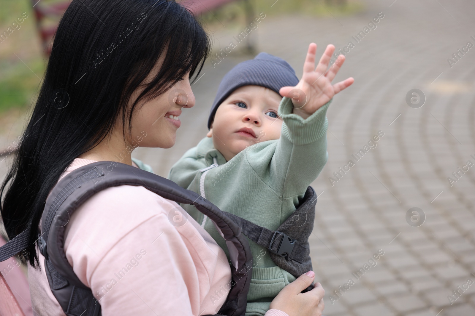 Photo of Mother holding her child in sling (baby carrier) outdoors