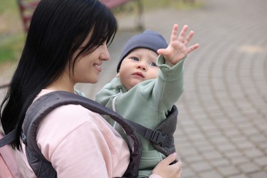 Mother holding her child in sling (baby carrier) outdoors