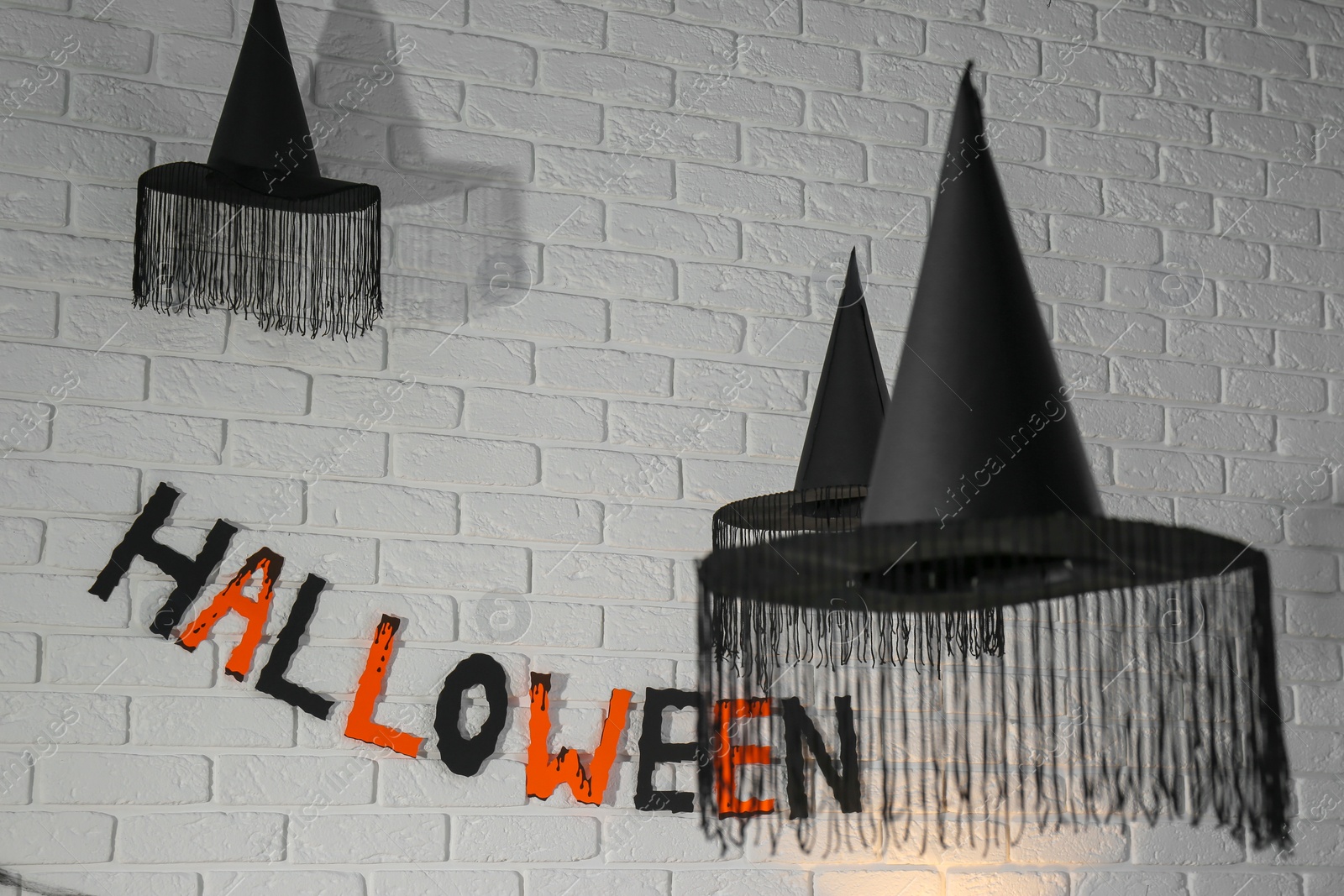 Photo of Word Halloween made of colorful letters and festive decor on brick wall