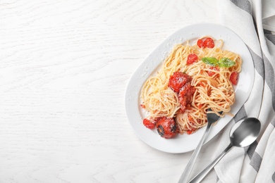 Tasty pasta and napkin on white wooden table, flat lay. Space for text