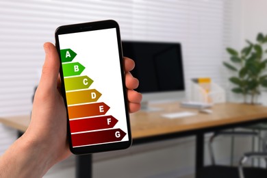 Image of Energy efficiency. Man using smartphone with colorful rating on display indoors, closeup