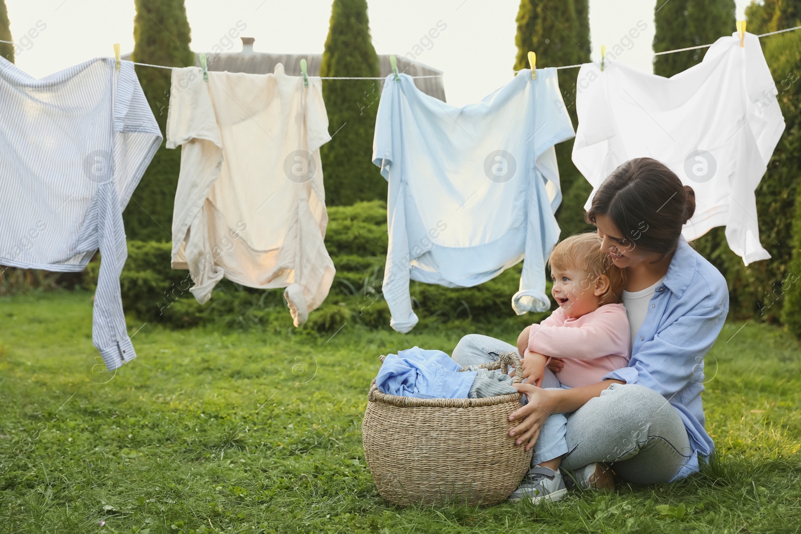 Photo of Mother and daughter near washing line with drying clothes in backyard