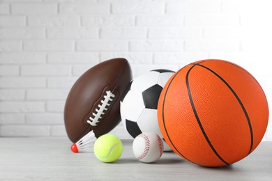 Photo of Set of different sport balls and shuttlecock on light wooden table