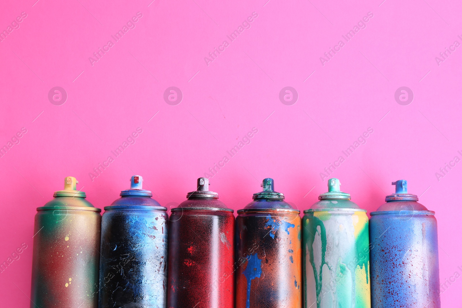 Photo of Many spray paint cans on pink background, flat lay. Space for text