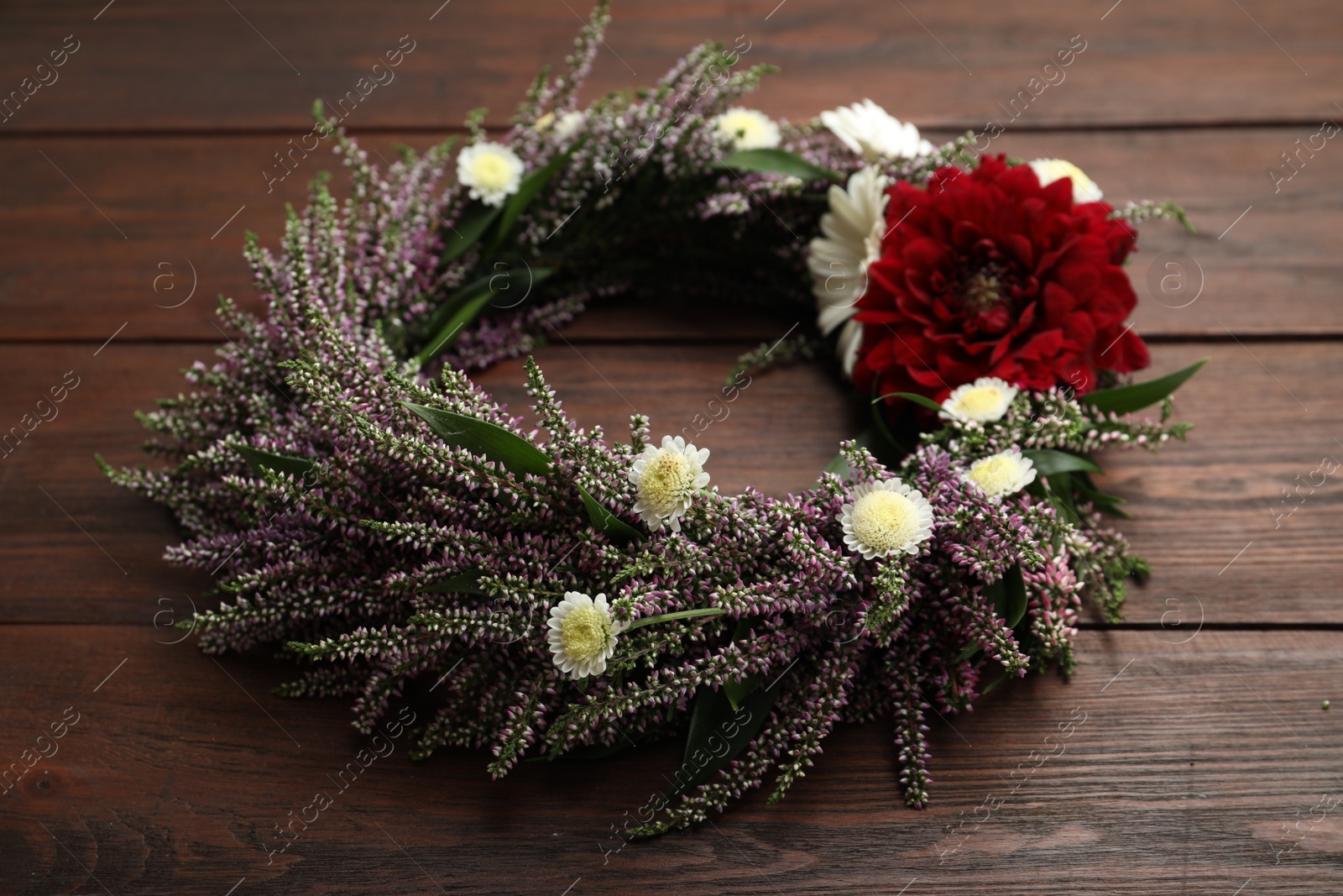 Photo of Beautiful autumnal wreath with heather flowers on wooden background, closeup
