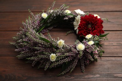 Beautiful autumnal wreath with heather flowers on wooden background, closeup