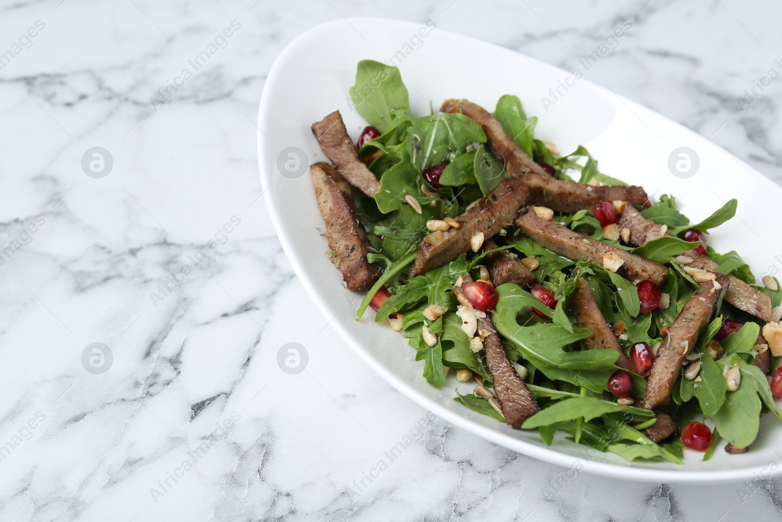 Photo of Delicious salad with beef tongue, arugula and seeds on white marble table. Space for text