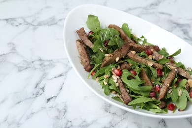 Delicious salad with beef tongue, arugula and seeds on white marble table. Space for text