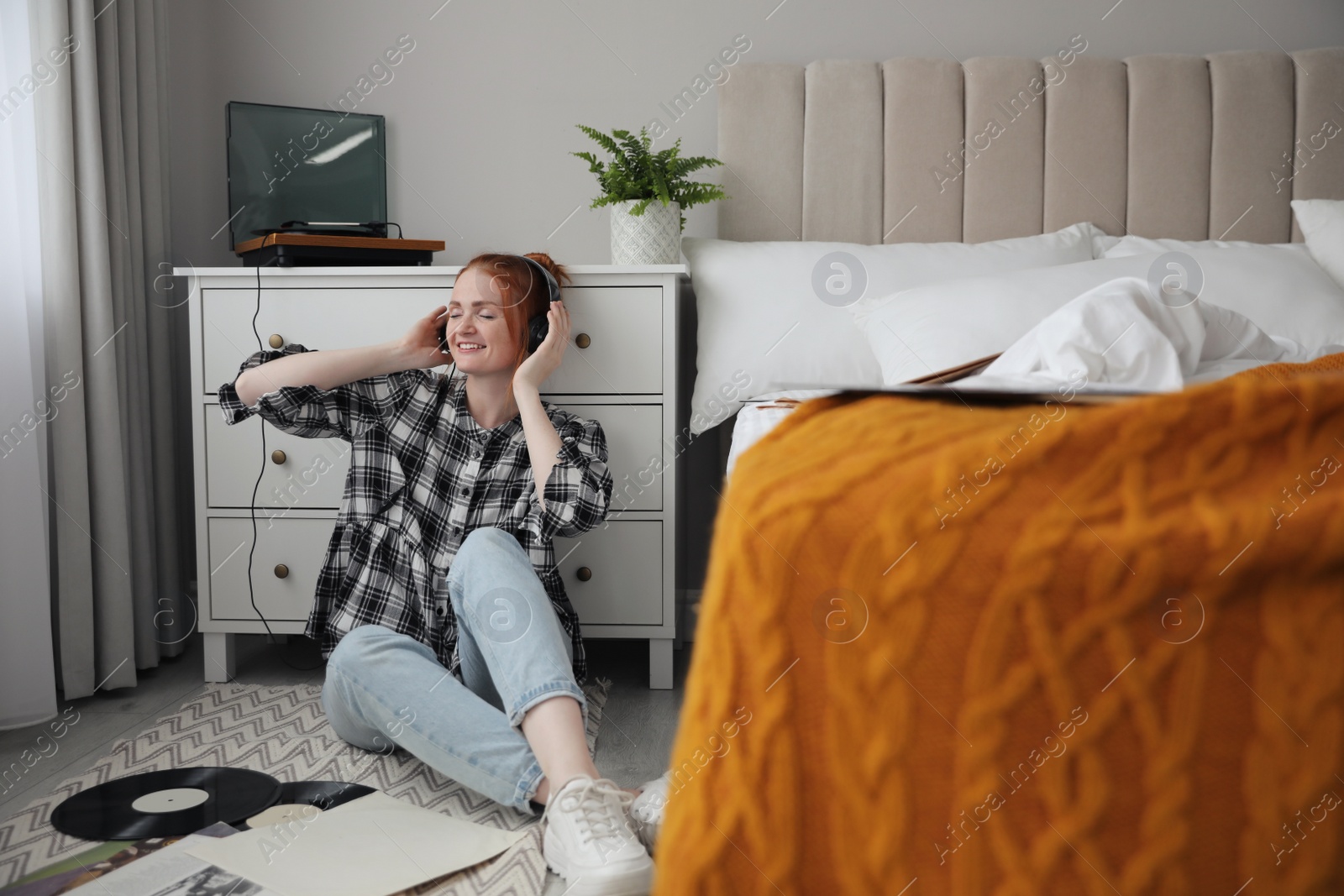 Photo of Young woman listening to music with turntable in bedroom