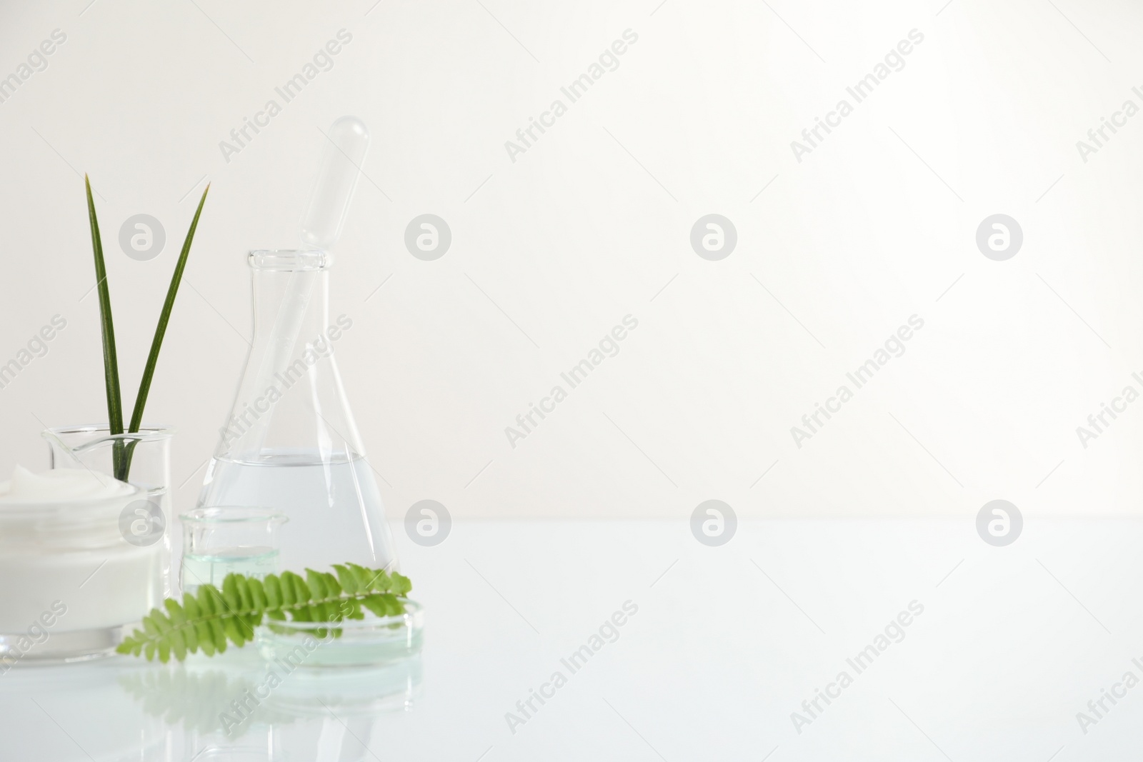 Photo of Organic cosmetic product, natural ingredients and laboratory glassware on white table, space for text