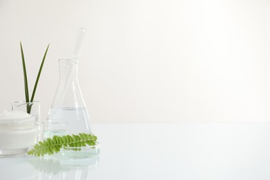 Organic cosmetic product, natural ingredients and laboratory glassware on white table, space for text