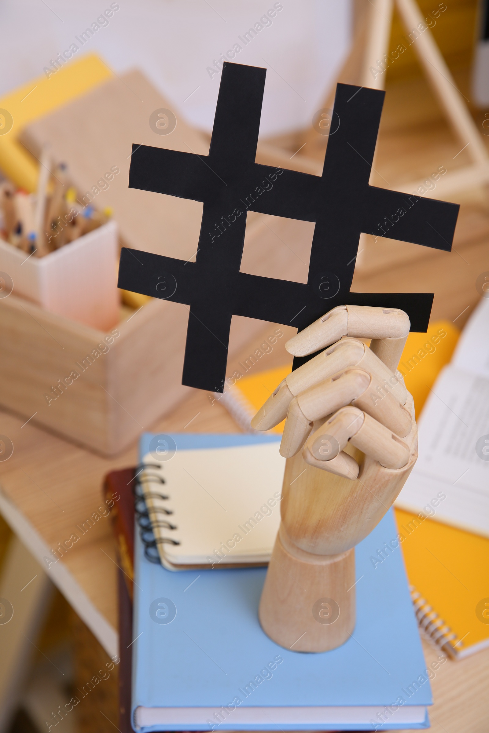 Photo of Wooden mannequin hand with paper hashtag symbol indoors