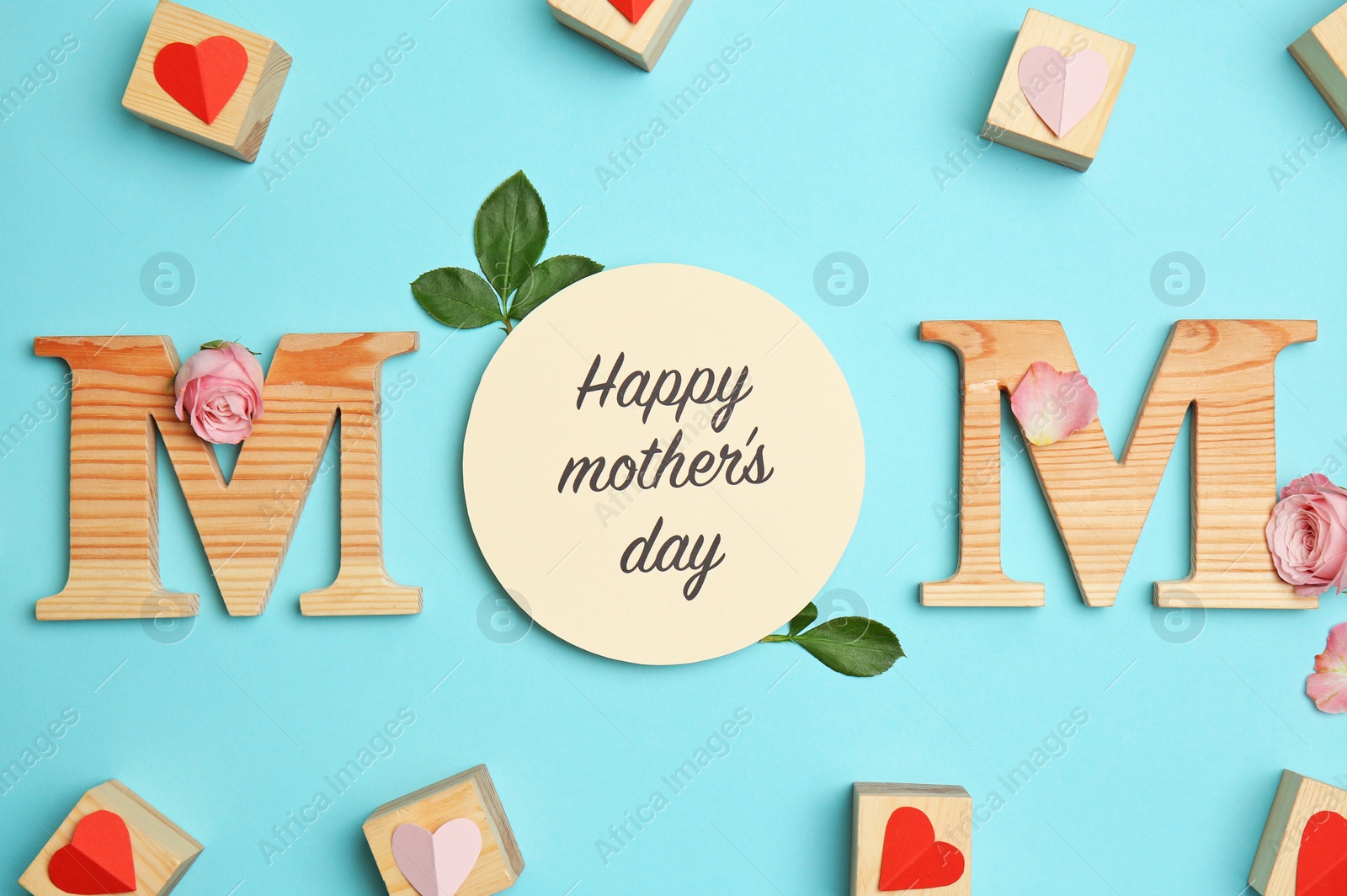 Photo of Word MOM made of letters with greeting card on color background. Flat lay composition for Mother's Day