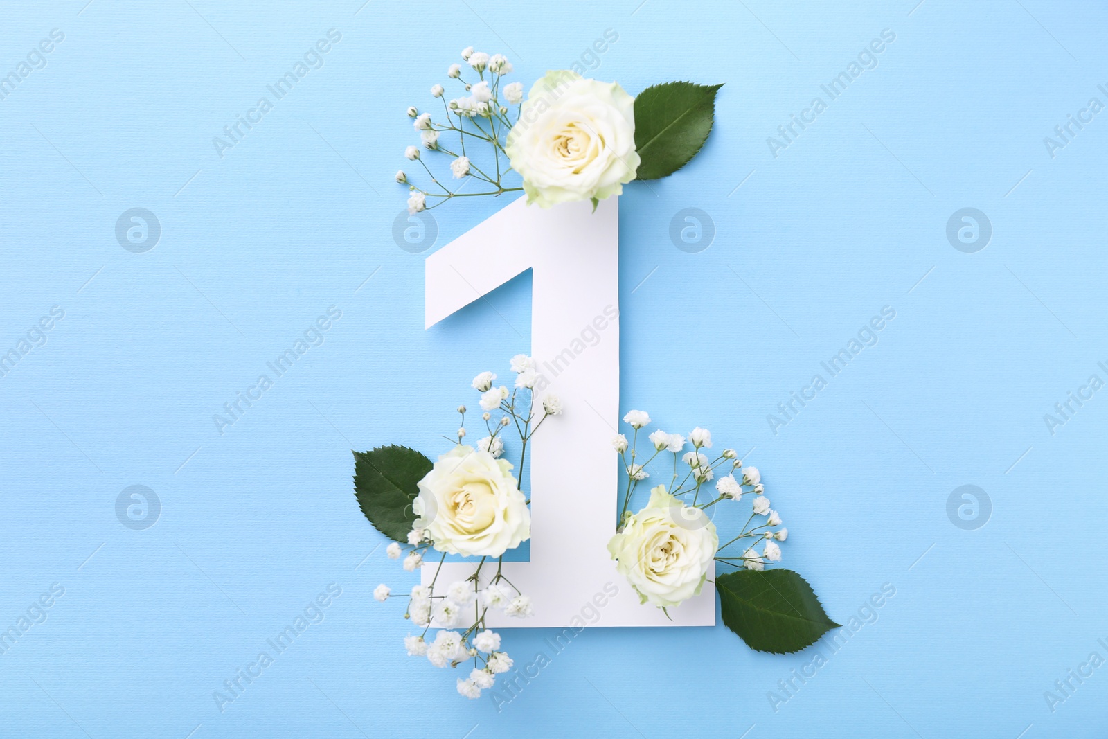 Photo of Paper number 1, beautiful flowers and green leaves on light blue background, top view