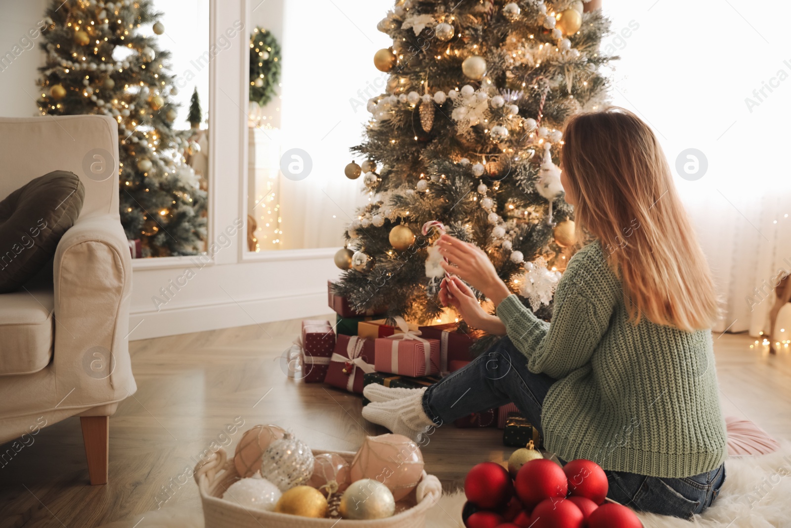 Photo of Woman decorating Christmas tree at home. Festive atmosphere