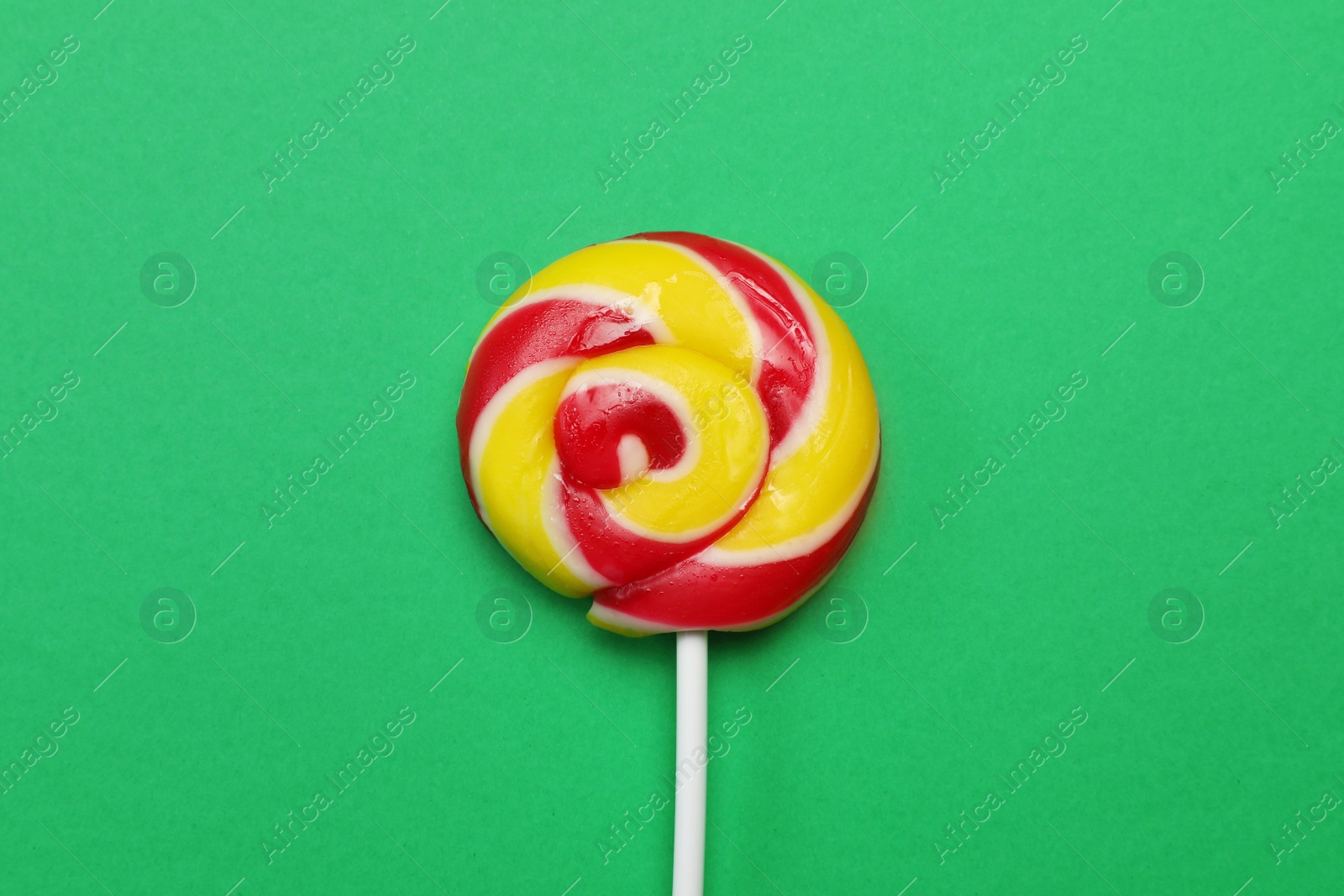 Photo of Sweet colorful lollipop on green background, top view