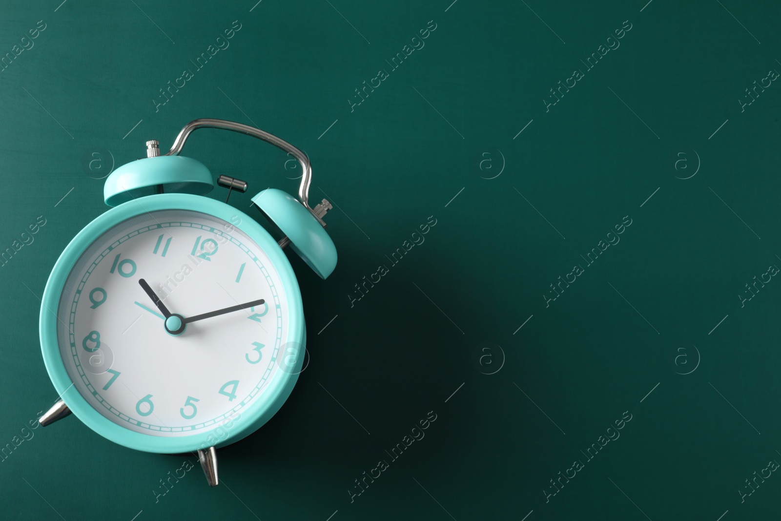 Photo of Alarm clock and space for text on green background, top view. School time