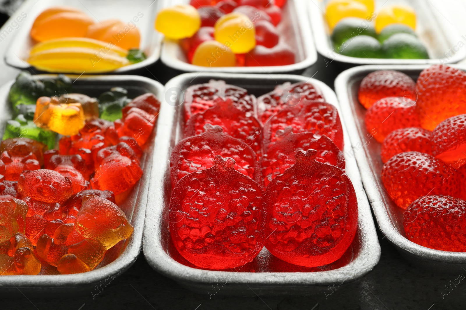 Photo of Different delicious gummy candies on grey table, closeup