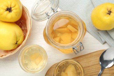 Photo of Delicious quince drink, fresh fruits and spoon on white wooden table, flat lay