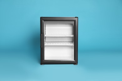 Photo of Empty mini bar with glass door on turquoise background