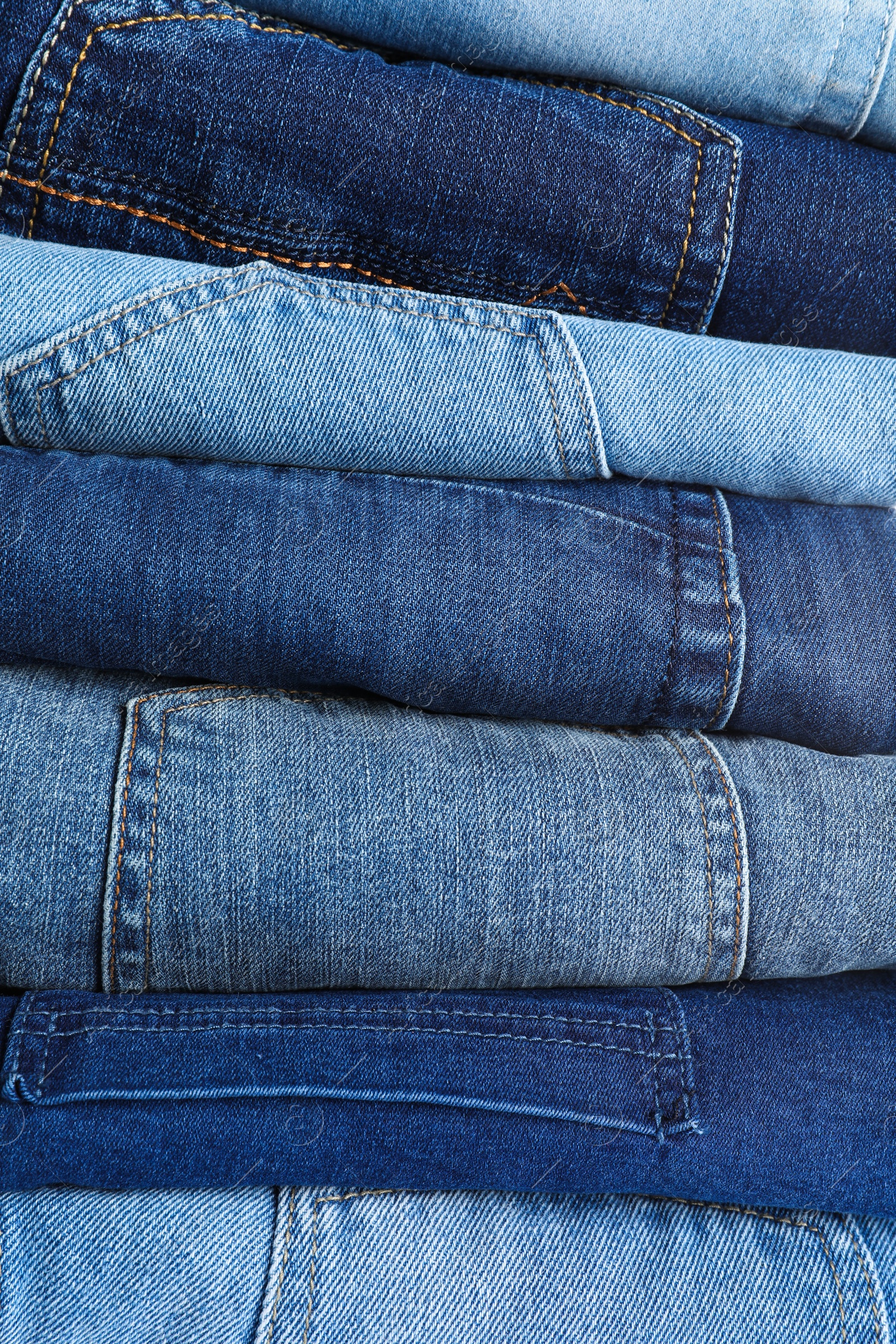 Photo of Stack of different jeans as background, closeup