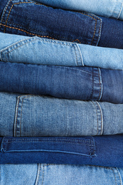 Stack of different jeans as background, closeup