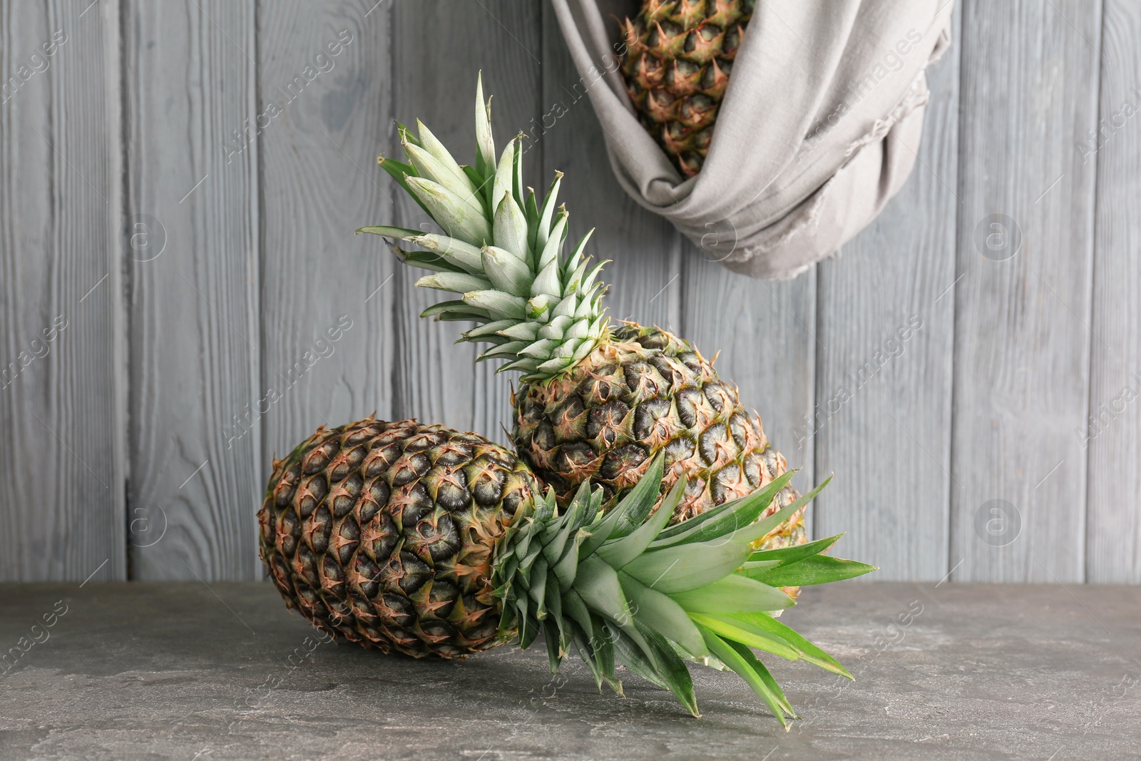 Photo of Fresh pineapples on table against wooden wall