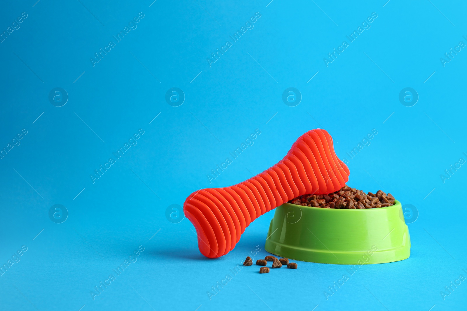 Photo of Pet toy and feeding bowl on light blue background, space for text