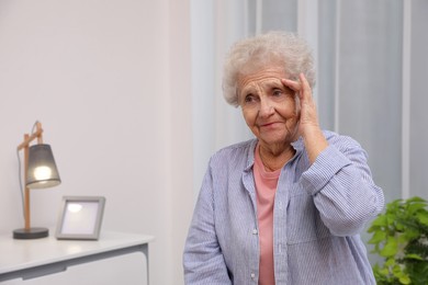 Photo of Senior woman with headache at home. Space for text
