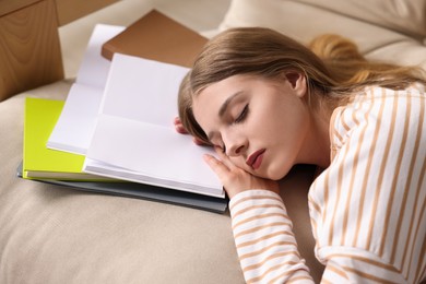 Photo of Young tired woman sleeping near books on couch, closeup