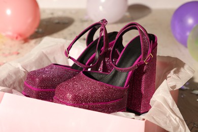 Photo of Stylish party. New pink high heeled shoes with platform and square toes in open box on floor, closeup