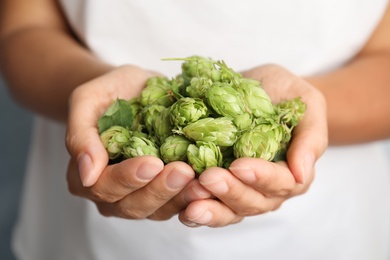 Photo of Woman holding fresh green hops, closeup. Beer production