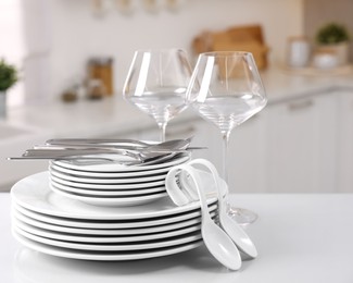 Photo of Set of clean dishware, glasses and cutlery on table in kitchen