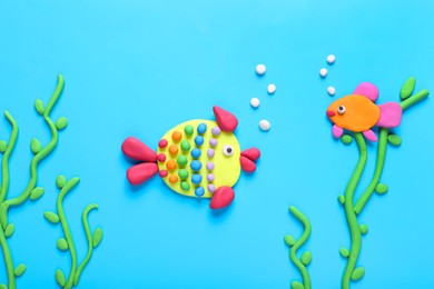 Photo of Seaweed and fish made of plasticine on light blue background, flat lay