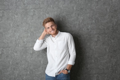 Portrait of handsome young man near grey wall